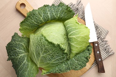 Photo of Fresh Savoy cabbage and knife on wooden table, top view
