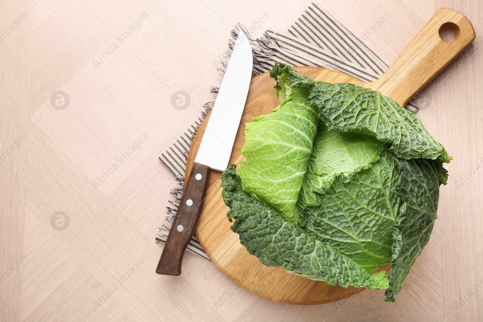 Photo of Fresh Savoy cabbage and knife on wooden table, top view. Space for text