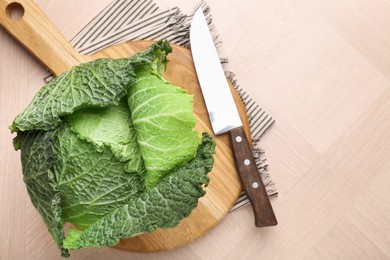 Photo of Fresh Savoy cabbage and knife on wooden table, top view. Space for text