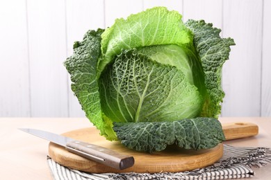 Photo of Fresh Savoy cabbage and knife on wooden table, closeup