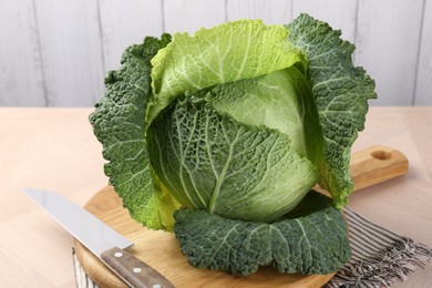 Photo of Fresh Savoy cabbage and knife on wooden table, closeup