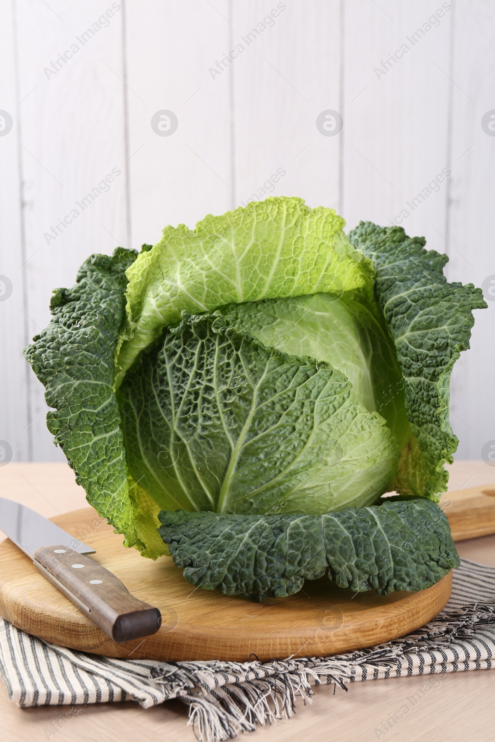 Photo of Fresh Savoy cabbage and knife on wooden table
