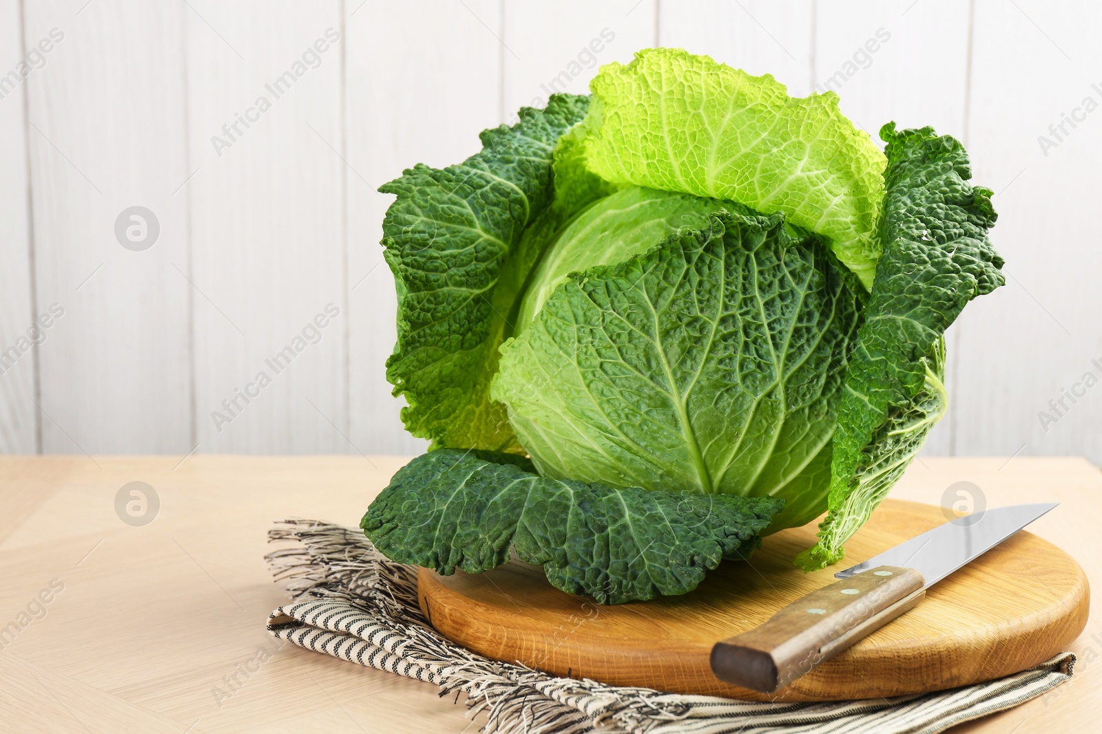 Photo of Fresh Savoy cabbage and knife on wooden table, closeup. Space for text