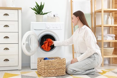 Photo of Woman putting dirty laundry into washing machine indoors