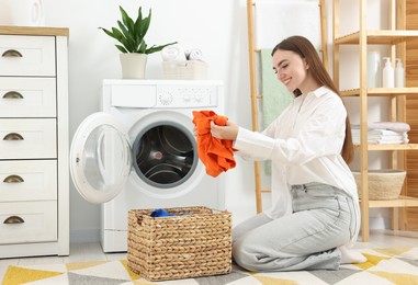 Photo of Woman with laundry near washing machine indoors