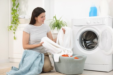 Photo of Woman with laundry near washing machine indoors