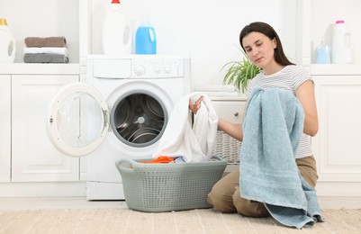 Photo of Woman with laundry near washing machine indoors