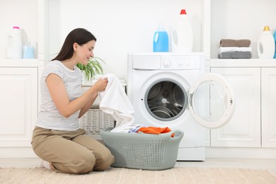 Photo of Woman with laundry near washing machine indoors