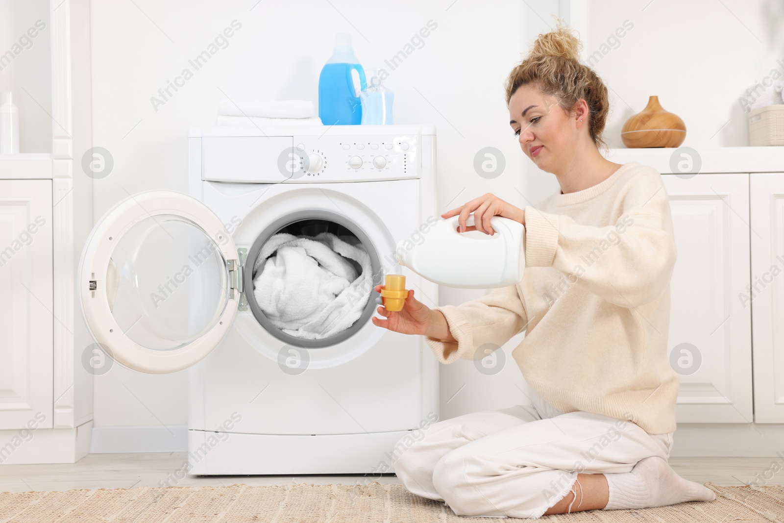 Photo of Woman pouring detergent into cap near washing machine in laundry room