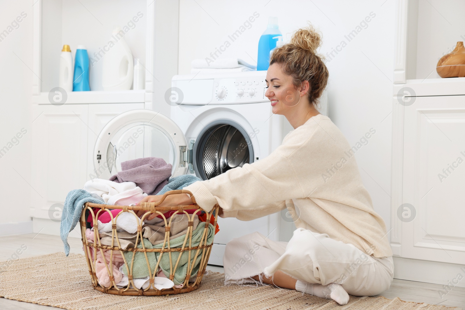 Photo of Woman with laundry near washing machine indoors