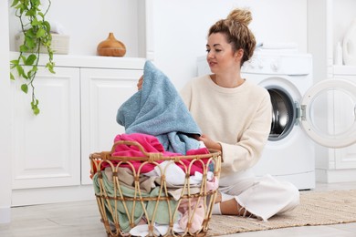 Photo of Woman with laundry near washing machine indoors