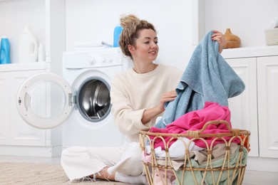 Photo of Woman with laundry near washing machine indoors