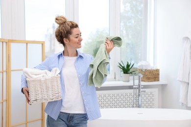 Photo of Woman with basket full of laundry indoors, space for text