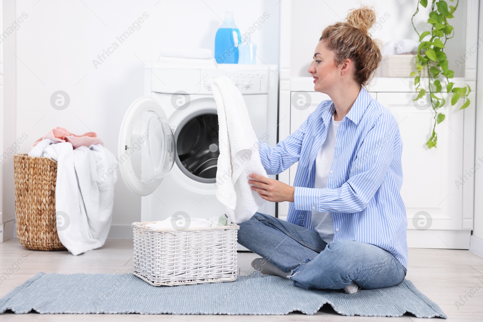 Woman with laundry near washing machine indoors Photo of Woman with laundry near washing machine indoors