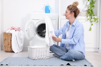 Photo of Woman with laundry near washing machine indoors