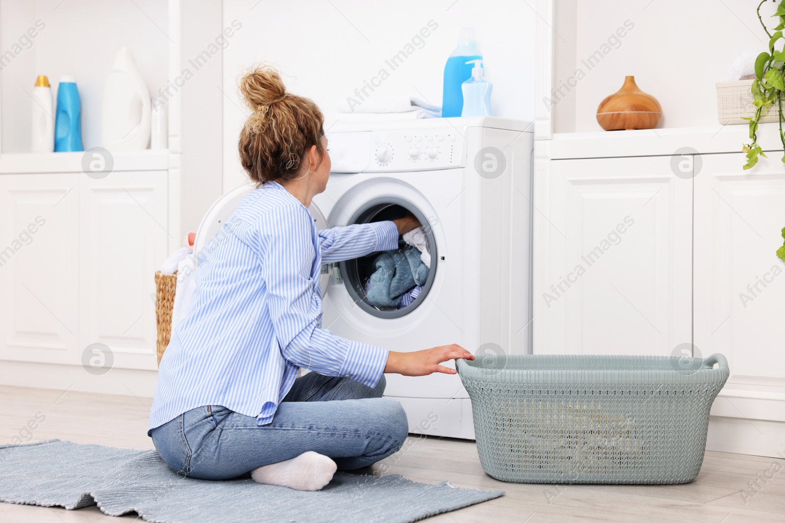 Woman putting dirty laundry into washing machine indoors Photo of Woman putting dirty laundry into washing machine indoors