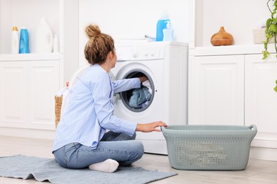 Photo of Woman putting dirty laundry into washing machine indoors