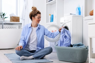 Photo of Woman with laundry near washing machine indoors