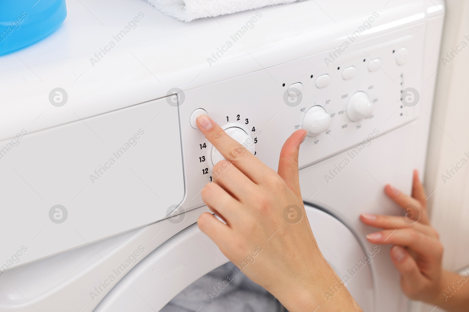 Woman using washing machine indoors, closeup. Laundry day Photo of Woman using washing machine indoors, closeup. Laundry day