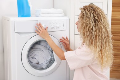 Photo of Woman using washing machine indoors, closeup. Laundry day