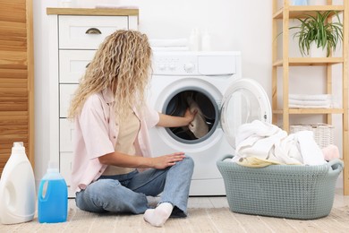 Photo of Woman putting dirty laundry into washing machine indoors