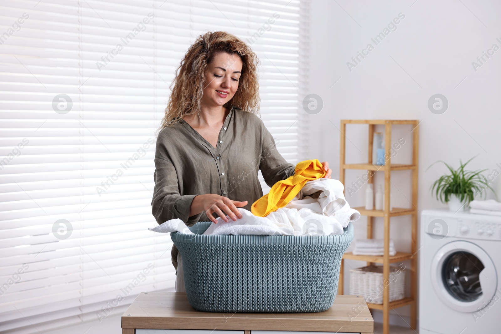 Photo of Woman with basket full of laundry indoors