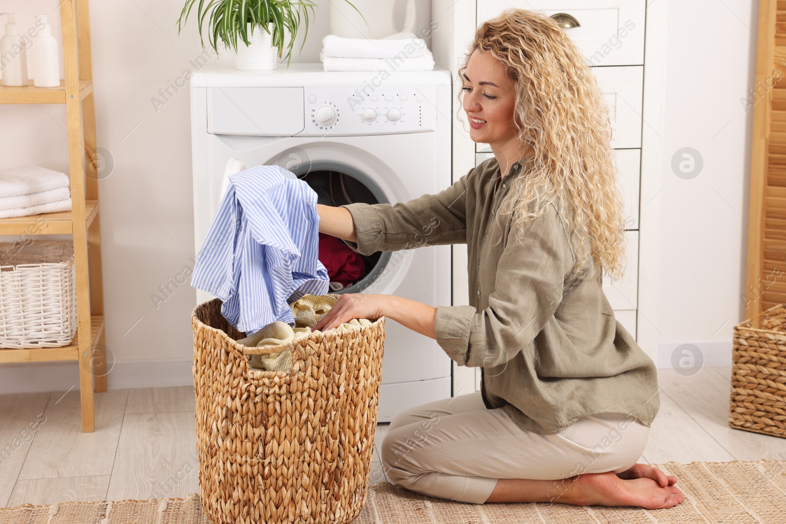 Woman with laundry near washing machine indoors Photo of Woman with laundry near washing machine indoors
