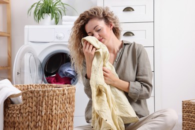 Photo of Woman with clean laundry near washing machine indoors