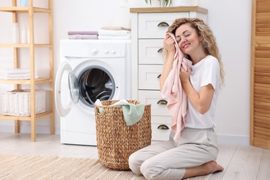 Photo of Woman with clean laundry near washing machine indoors