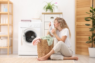Photo of Woman with clean laundry near washing machine indoors