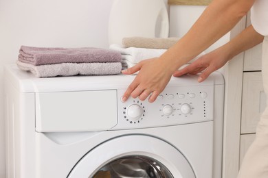 Photo of Woman using washing machine indoors, closeup. Laundry day