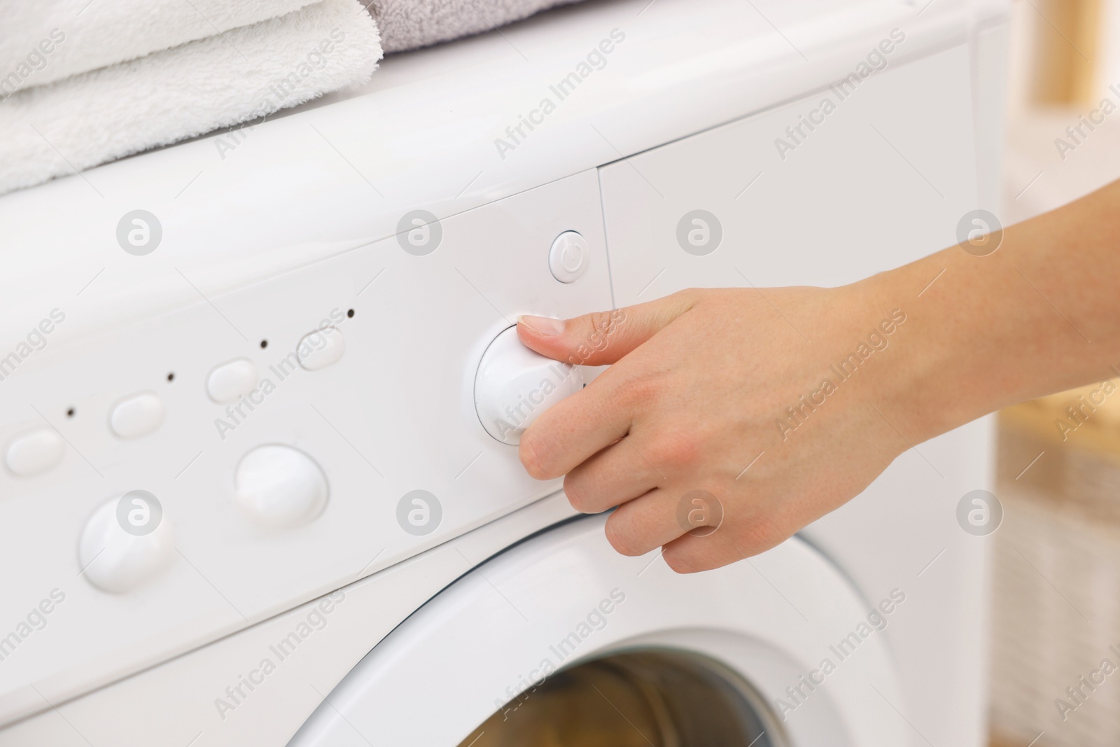 Woman using washing machine indoors, closeup. Laundry day Photo of Woman using washing machine indoors, closeup. Laundry day