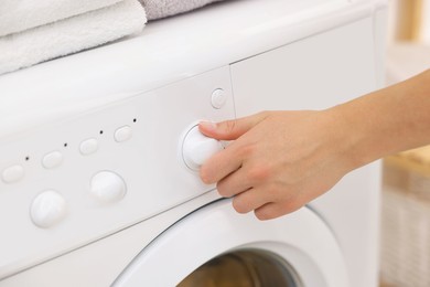 Photo of Woman using washing machine indoors, closeup. Laundry day