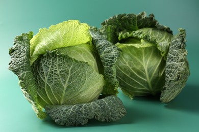 Photo of Fresh Savoy cabbages on teal background, closeup