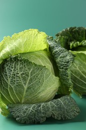 Photo of Fresh Savoy cabbages on teal background, closeup