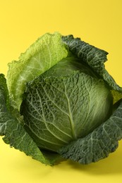 Photo of One fresh Savoy cabbage on yellow background, closeup