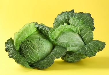 Photo of Fresh Savoy cabbages on yellow background, closeup