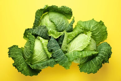 Photo of Fresh Savoy cabbages on yellow background, flat lay