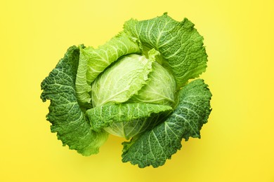 Photo of One fresh Savoy cabbage on yellow background, top view
