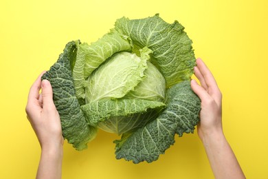 Photo of Woman with fresh Savoy cabbage on yellow background, top view
