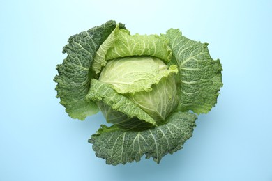 Photo of One fresh Savoy cabbage on light blue background, top view