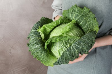 Photo of Woman holding fresh Savoy cabbage on grey background, closeup