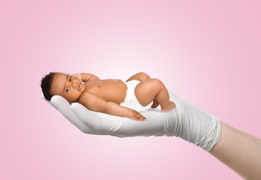Image of In vitro fertilization (IVF). Cute little baby in doctor's hand against pink background