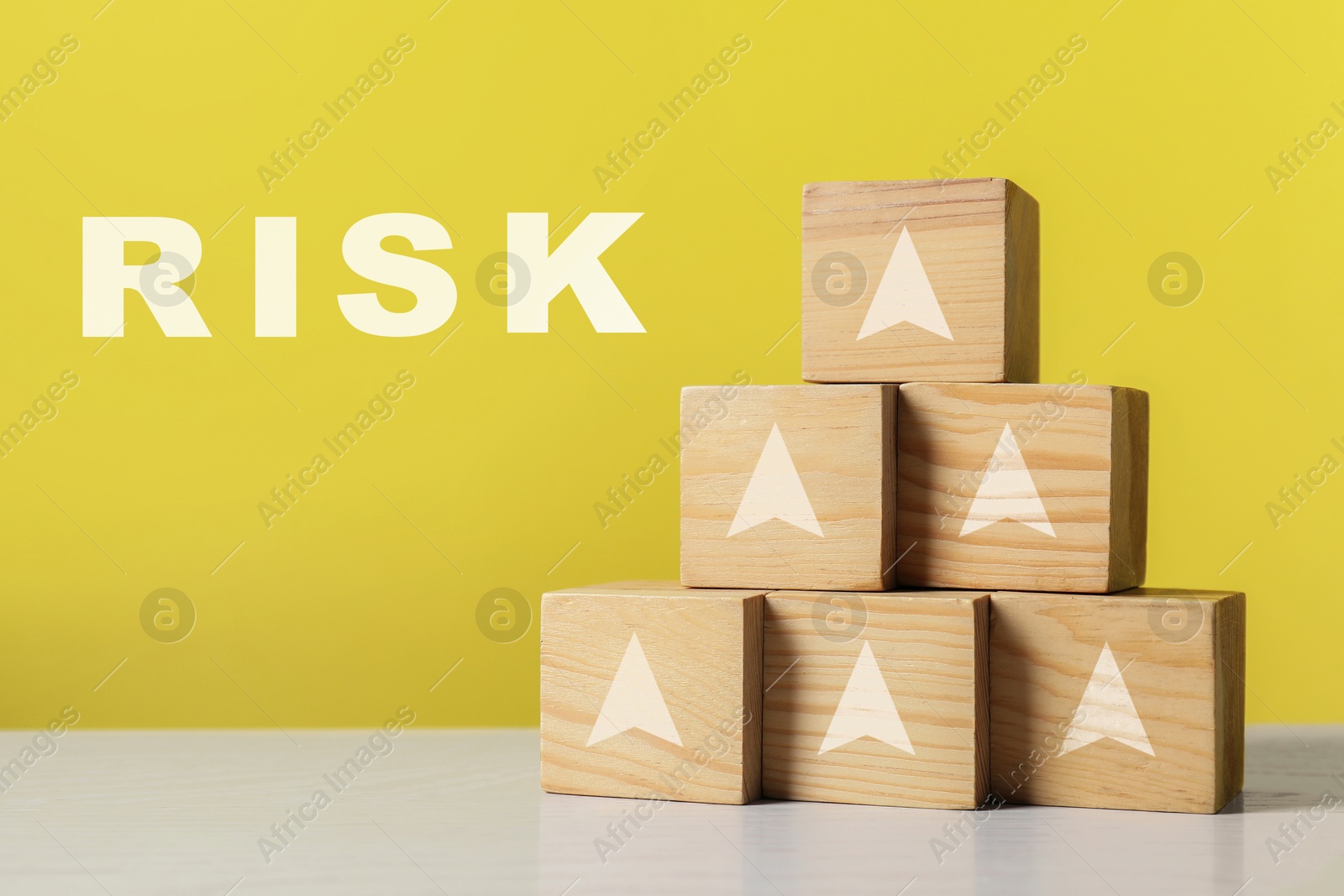 Image of Risk. Pyramid of wooden cubes with arrows against yellow background