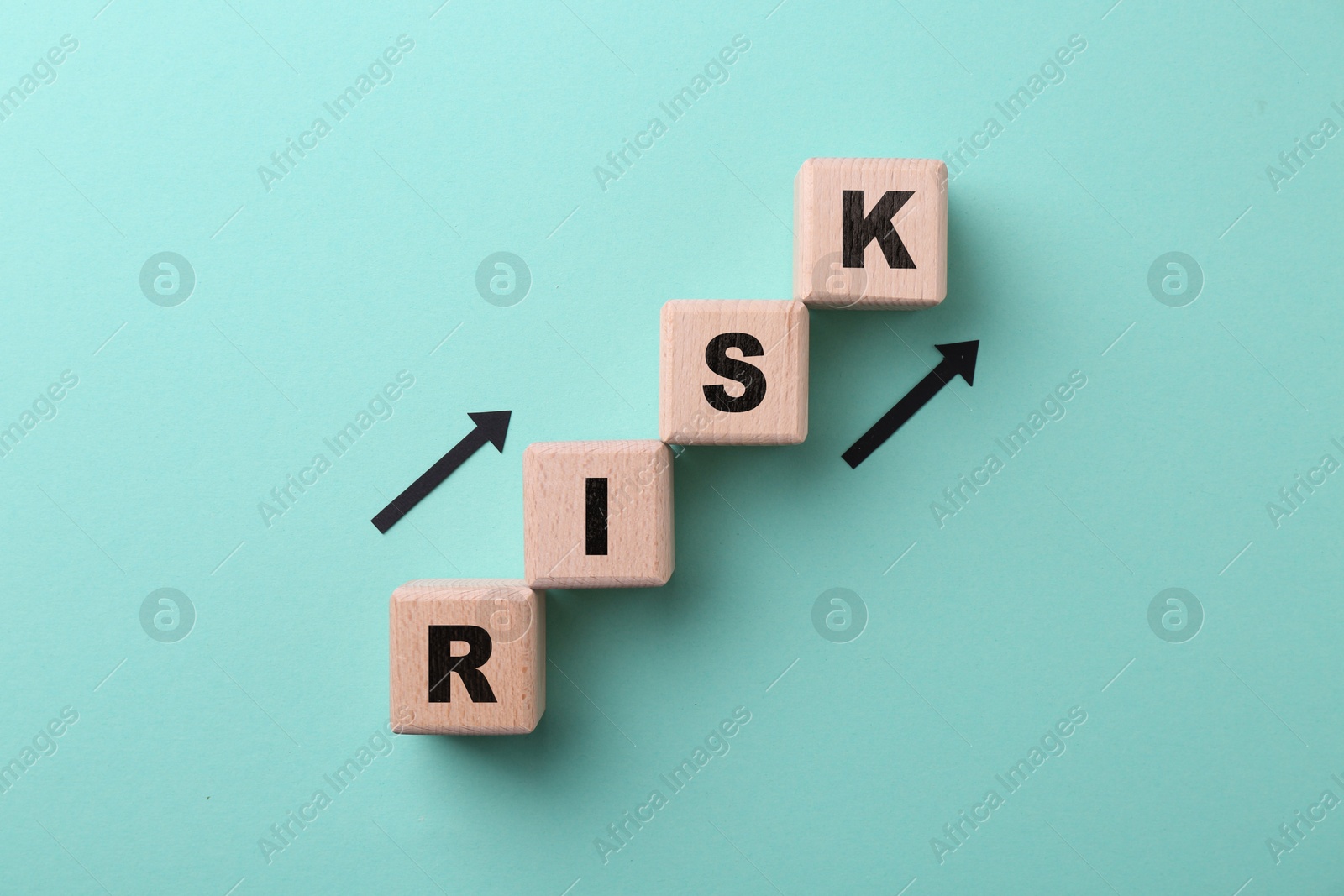 Image of Word Risk of wooden cubes with letters and arrows on turquoise background, top view