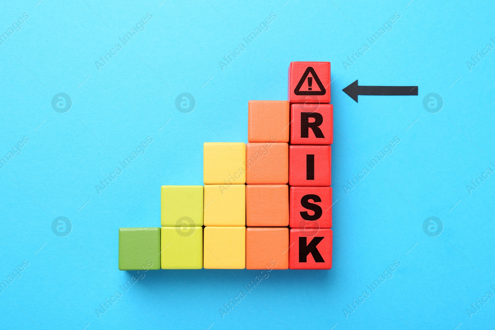 Image of Word Risk of wooden cubes with letters on light blue background, top view. Arrow pointing at warning sign