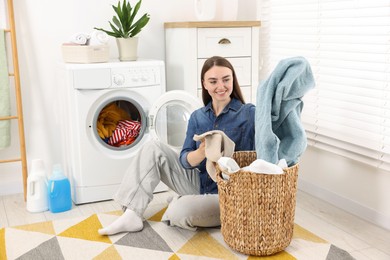 Photo of Woman with laundry near washing machine indoors