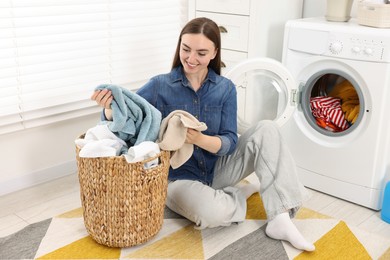 Photo of Woman with laundry near washing machine indoors