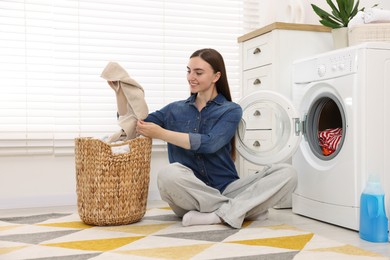 Photo of Woman with laundry near washing machine indoors