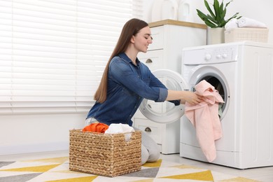 Photo of Woman putting dirty laundry into washing machine indoors